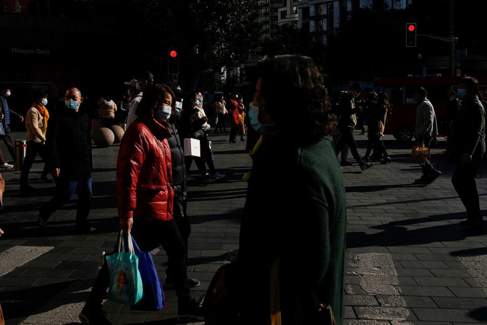 People wearing protective masks walk on a street, following new cases of the coronavirus, in Shanghai, China, November 24. &mdash; Reuters