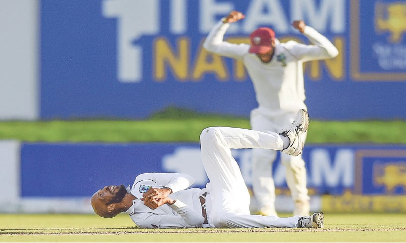 WEST INDIES bowler Roston Chase (bottom) takes a catch to dismiss 
Sri Lankan captain Dimuth Karunaratne during the second Test at the Galle International Stadium on Monday.—AFP