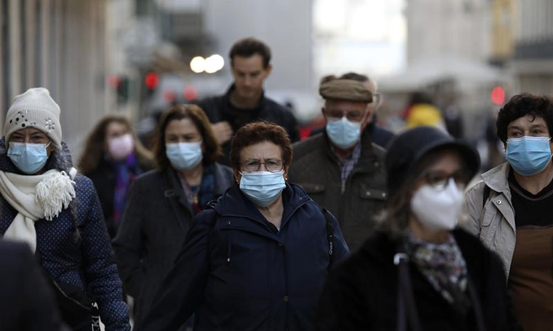 People wearing face masks to curb the spread of Covid-19 walk in downtown Lisbon on Monday. — AP