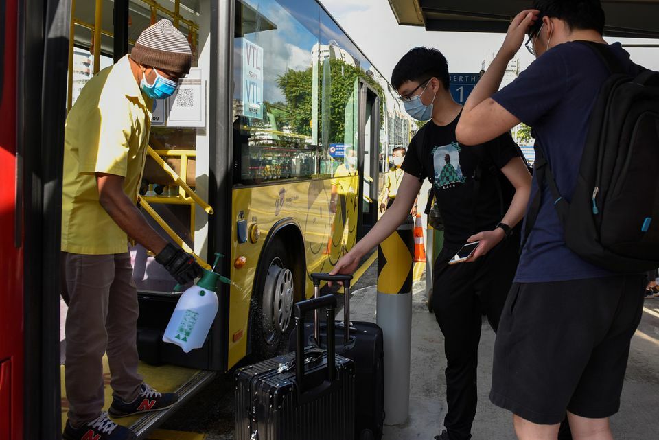 A bus driver sprays disinfectant on the luggage of passengers travelling to Malaysia at a bus station in Singapore, November 29. — Reuters