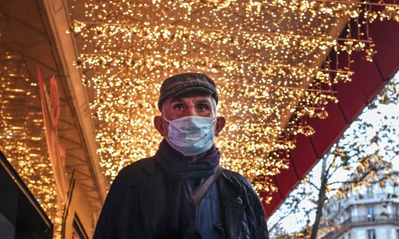 A man wearing a face mask to protect against coronavirus walks of Christmas lighting in Paris on Nov 30. &mdash; AP
