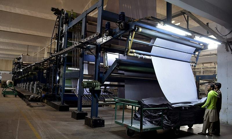 In this file photo, workers operate a machine at a textile factory in Faisalabad. — AFP/File