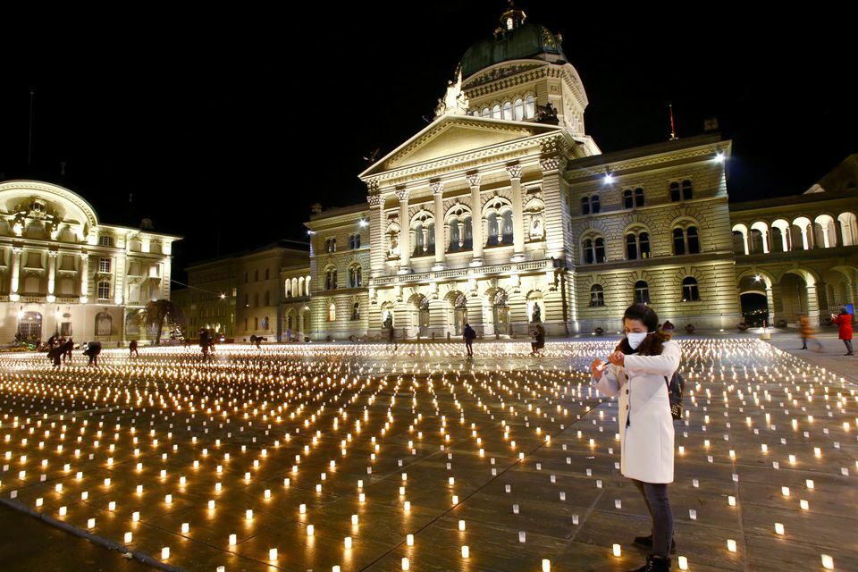 A woman lights one of more than 11,000 candles during a candlelight vigil in front of the seat of the Swiss federal parliament Bundeshaus in Bern, Switzerland, December 7. — Reuters