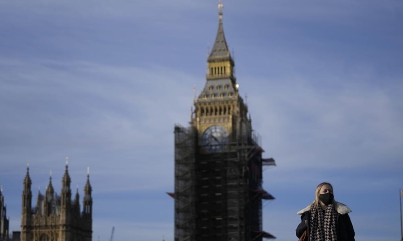 A woman wears a face mask as she crosses Westminster Bridge in London, UK, Dec 9. &mdash; AP