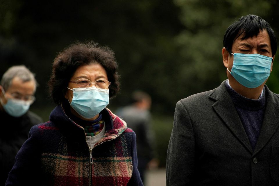 People wearing face masks following the coronavirus outbreak walk on a street in Shanghai, China, December 14. — Reuters