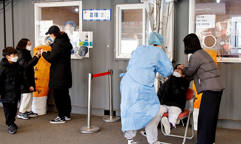 A healthcare worker collects a swab sample from a boy to test for coronavirus, at a temporary testing site set up at a railway station, in Seoul, South Korea. — Reuters