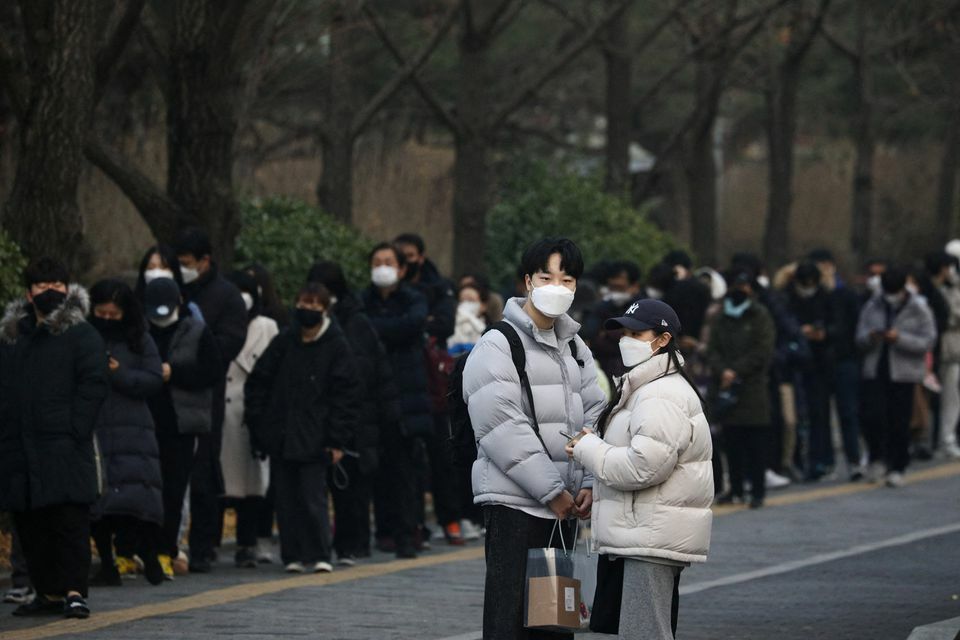 A couple stands next to people waiting in a long line to undergo a coronavirus test at a testing site in Seoul, South Korea, December 15. &mdash; Reuters