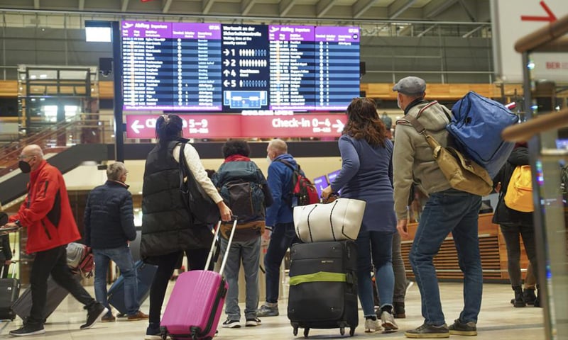 Travellers stand in front of an information board at BER Airport in Berlin, Germany. — AP