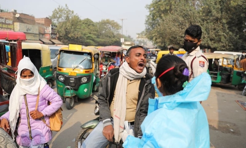 A healthcare worker collects a coronavirus disease test swab sample from a man on a road in New Delhi on December 6. — Reuters