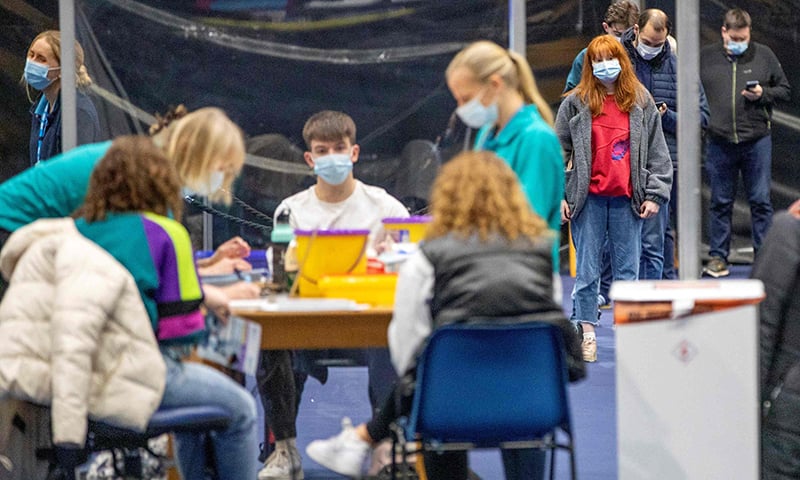 Members of the public receive a dose of a Covid-19 vaccine at a temporary vaccination centre set up in the Titanic Exhibition Centre in Belfast, UK, on Tuesday. — AFP