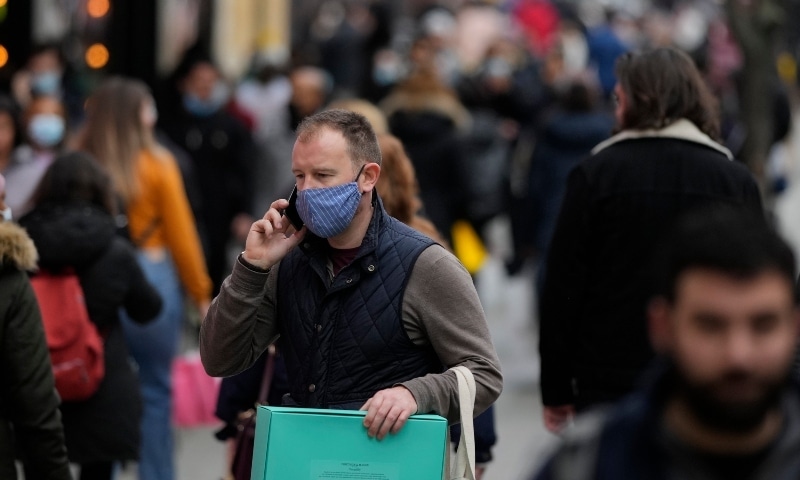 A shopper wearing a face mask against the ongoing pandemic carries his bags after leaving a department store in Oxford Street on Christmas Eve in London on Dec 24. &mdash; AP