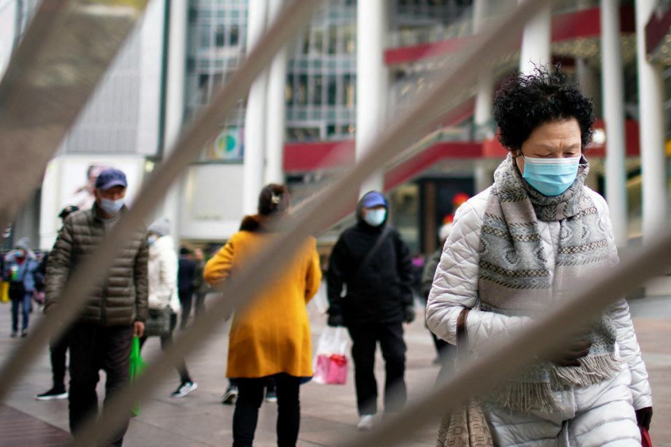 People wearing face masks following the coronavirus outbreak walk on a shopping street in Shanghai, China, December 14. &mdash; Reuters