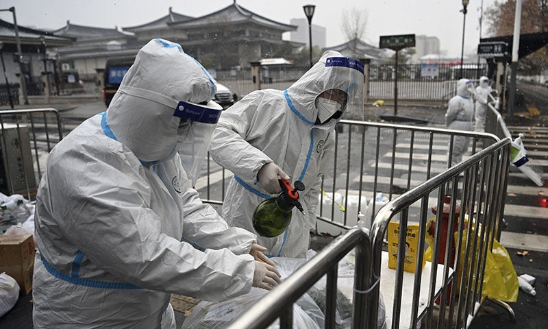 In this photo released by Xinhua News Agency, workers wearing protective suits disinfect packed vegetables at a residential area under quarantine in Xi'an in northwestern China's Shaanxi Province. &mdash; AP