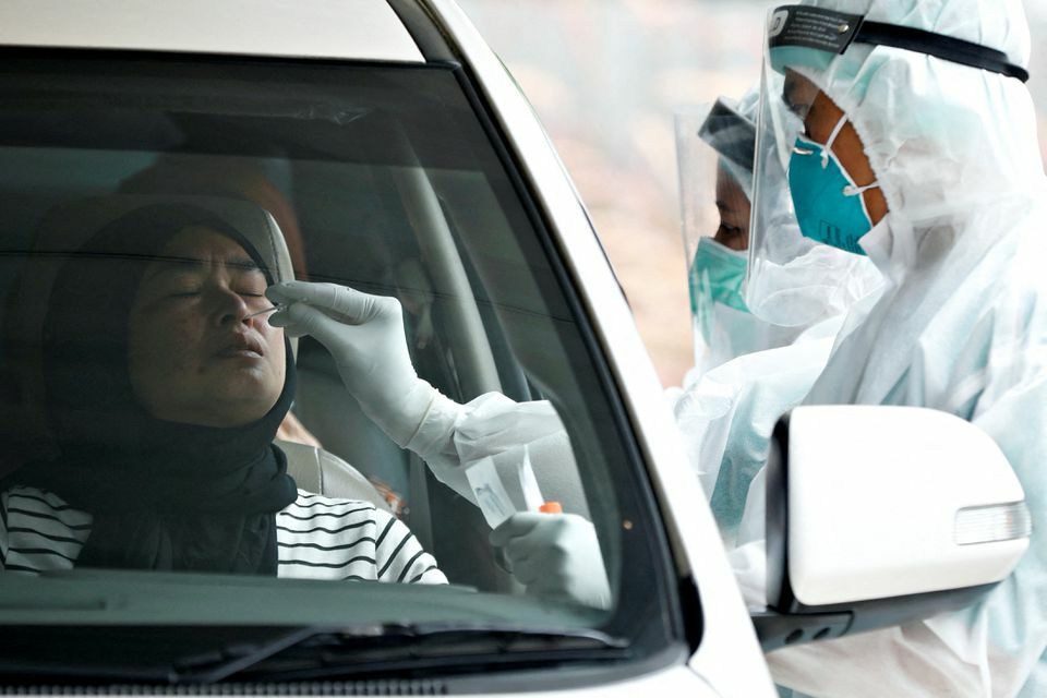 A healthcare worker wearing personal protective equipment takes a swab sample to test for the coronavirus at a drive-through testing site in Jakarta, Indonesia, December 16. — Reuters