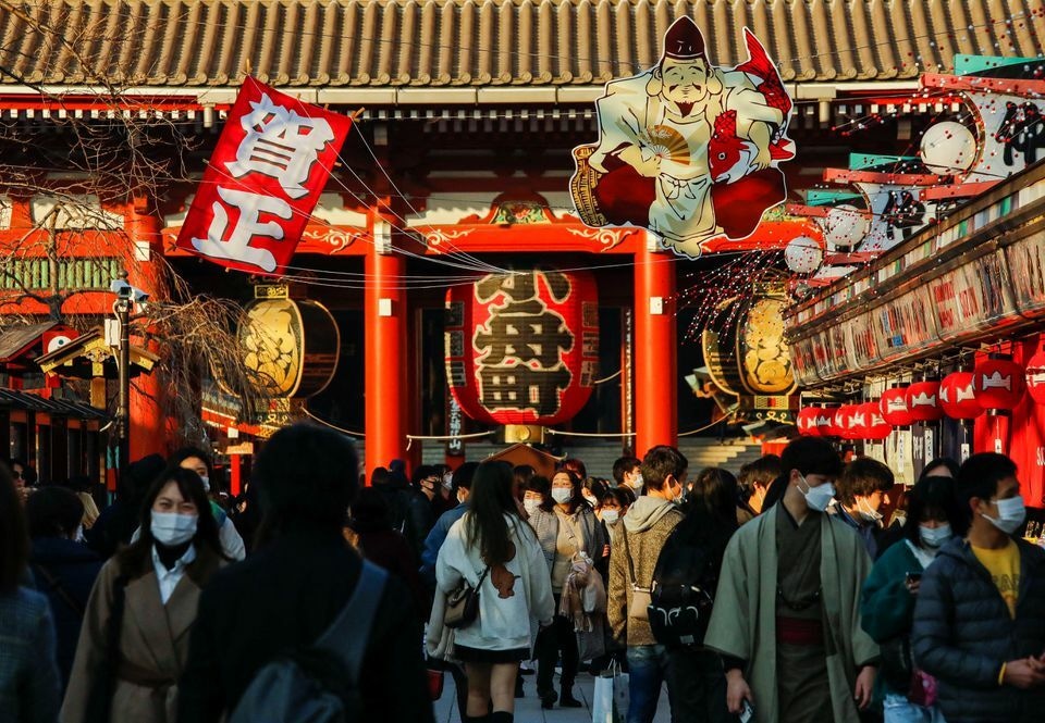 Visitors wearing protective face masks walk under decorations for the New Year at Nakamise street leading to Senso-ji temple at Asakusa district in Tokyo, Japan, December 24. &mdash; Reuters