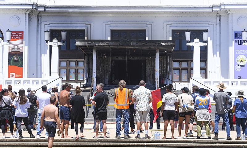 THE protesters stand in front of the damaged entrance doors to the old parliament building.—AP