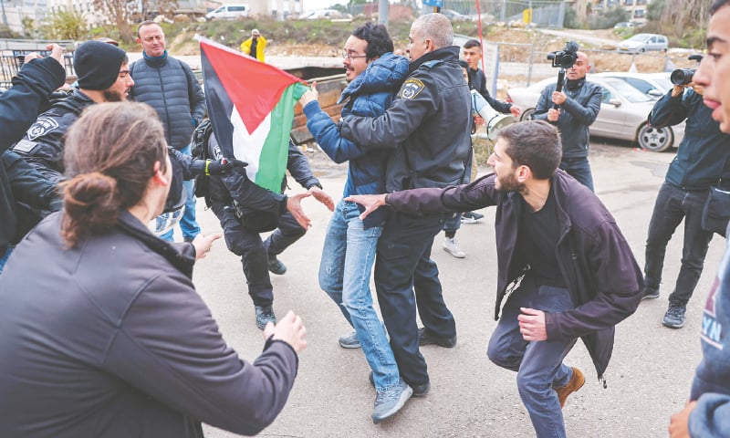 SHEIKH JARRAH: Israeli soldiers detain a man holding a Palestinian flag during a demonstration on Friday to denounce the evacuation of Palestinian families from their homes and settlement activity in the occupied territories.—AFP