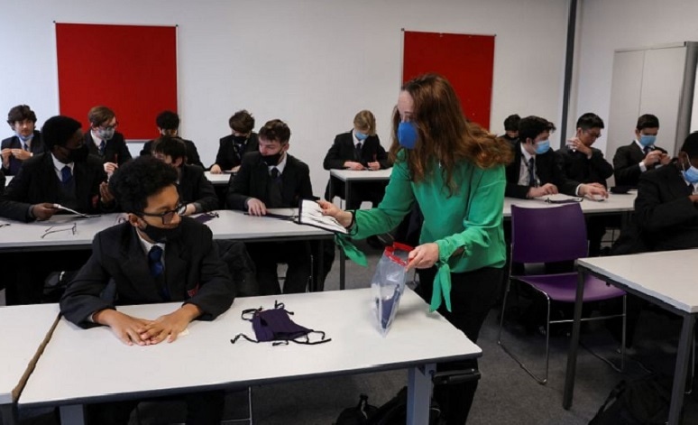 In this file photo, a teacher hands out face masks to students on the first day back at school, as the Covid-19 lockdown begins to ease at Fulham Boys School in London on March 8, 2021. — Reuters/File