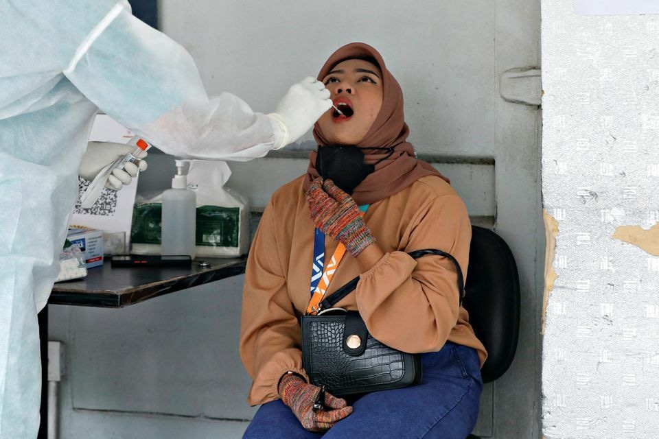 A healthcare worker wearing personal protective equipment takes a swab sample to test for the coronavirus in Jakarta, Indonesia, December 16. — Reuters