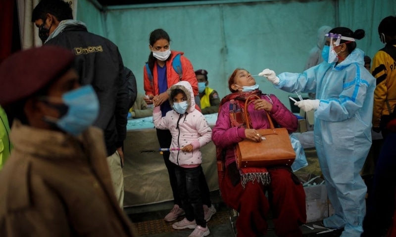 A healthcare worker collects a coronavirus test swab sample from a woman amidst the spread of the disease, at a railway station in New Delhi, India, January 5. — Reuters