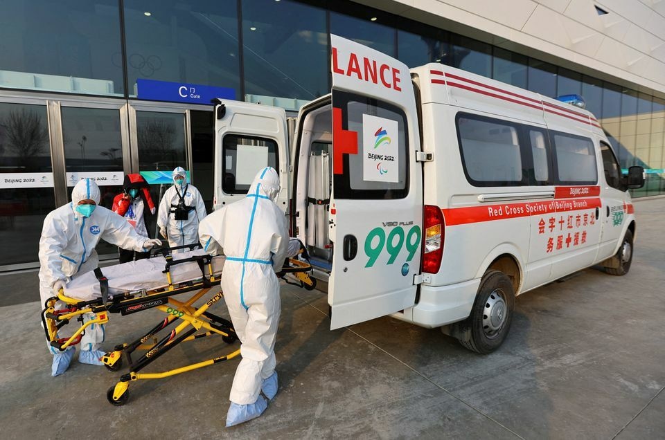 Red cross ambulance staff wearing protective suits to protect from the coronavirus load a stretcher into an ambulance, outside the Main Press Centre ahead of the Beijing 2022 Winter Olympics in Beijing, China, January 7. &mdash; Reuters