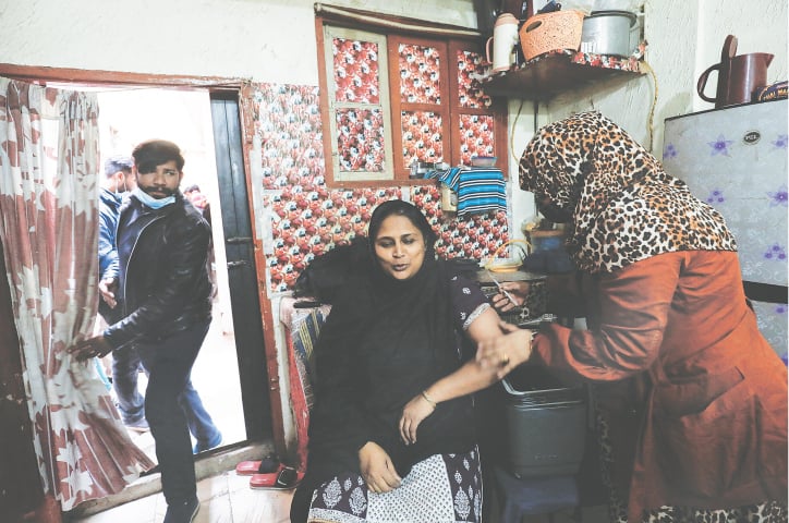 KARACHI: A woman reacts as she receives a Covid-19 vaccine during a door-to-door vaccination campaign on Tuesday.—Reuters