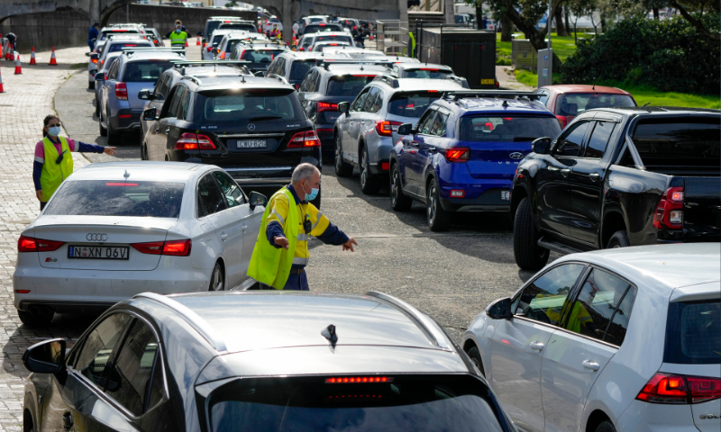 Traffic marshalls direct cars at a drive-through Covid-19 testing clinic at Bondi Beach in Sydney, Australia. &mdash; AP/File