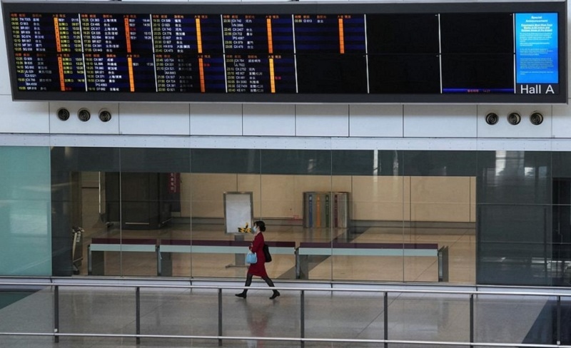 A flight attendant walks under an information board at the arrivals hall of Hong Kong International Airport, following infections of the coronavirus disease in Hong Kong on Jan 11, 2022. — Reuters