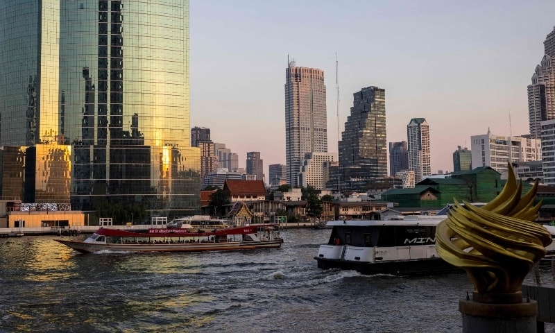 Two boats pass each other on the Chao Phraya River in front of the Bangkok skyline on January 17. — AFP