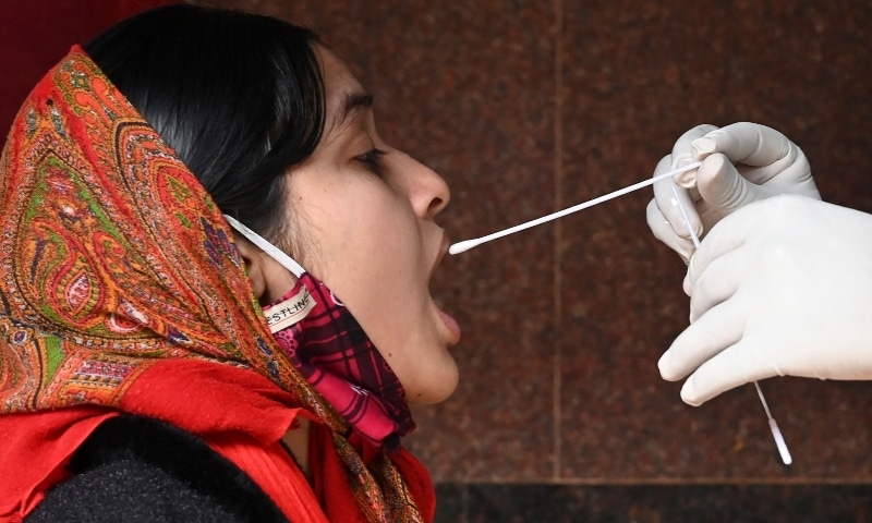 A health worker collects a swab sample from a woman to test for Covid-19 at a government hospital in Kolkata on January 18. &mdash; AFP