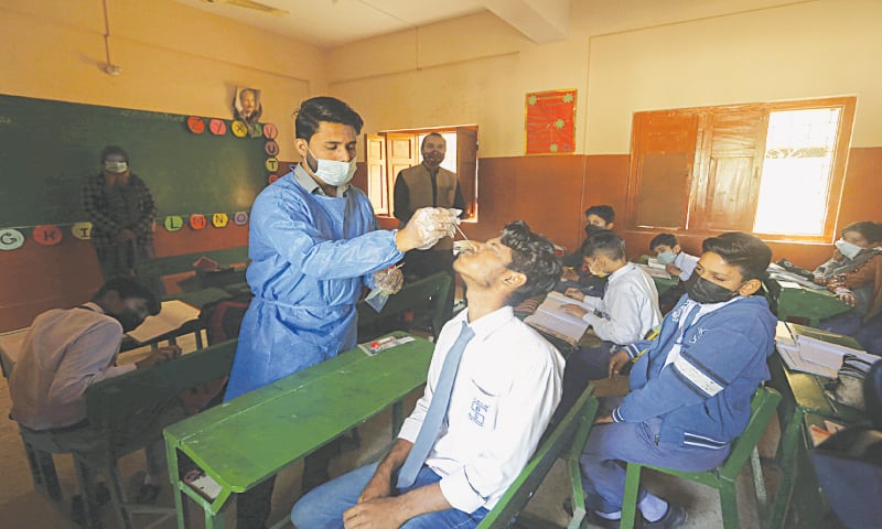 A health worker takes a nasal swab sample from a student to conduct random testing for the coronavirus at a school in Karachi on Wednesday.—AP