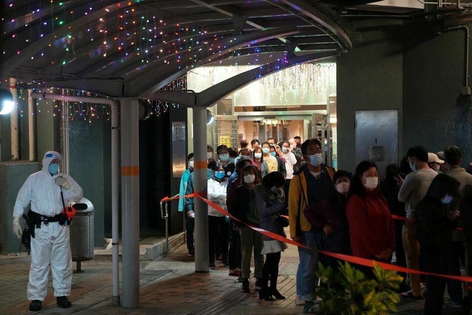 A health worker wearing a protective suit stands as residents queue for taking a nucleic acid test for the coronavirus at a makeshift testing site in Hong Kong, China, January 22. — Reuters