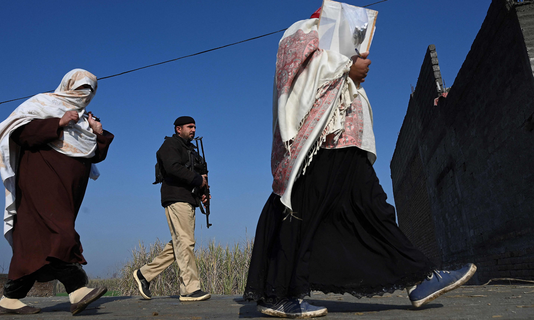 A policeman (C) escorts health workers during a door-to-door polio vaccination campaign.