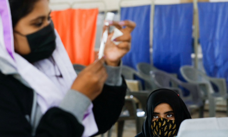 A girl waits as a healthcare worker prepares a dose of coronavirus vaccine to administer at a vaccination centre in Karachi in this Jan 21 file photo. — Reuters