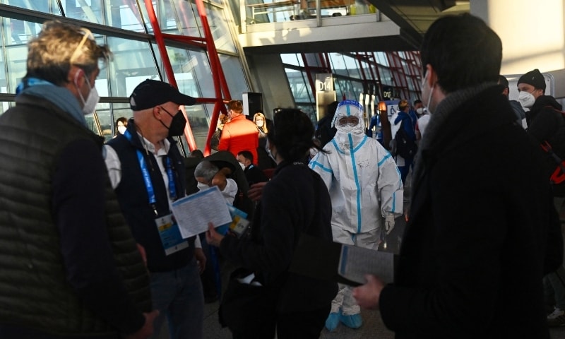 A staff member wearing personal protective equipment directs passengers as they arrive at the Beijing Capital International Airport ahead of the Beijing 2022 Winter Olympics in Beijing, China, January 29. &mdash; Reuters