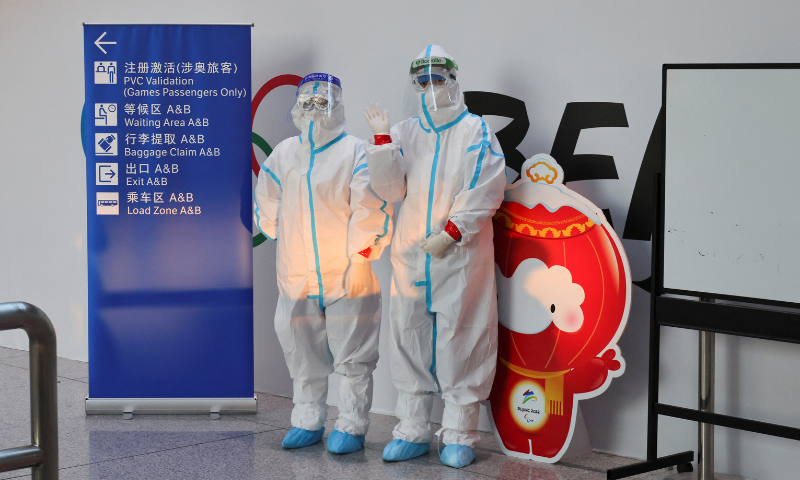 Staff members wearing personal protective equipment (PPE), designed to prevent the spread of the coronavirus, welcome passengers as they arrive at Beijing Capital International Airport ahead of the Beijing 2022 Winter Olympics in Beijing, China. — Reuters