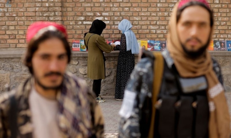 Two girls search for books in a book stall outside the Kabul university while two Taliban soldiers pose after asking to be photographed, in Kabul, Afghanistan, October 5, 2021. — Reuters/File