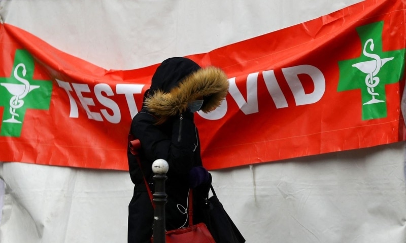 A person, wearing a protective face mask, walks past a tent for a rapid coronavirus test in the streets of Paris, France, January 31. &mdash; Reuters