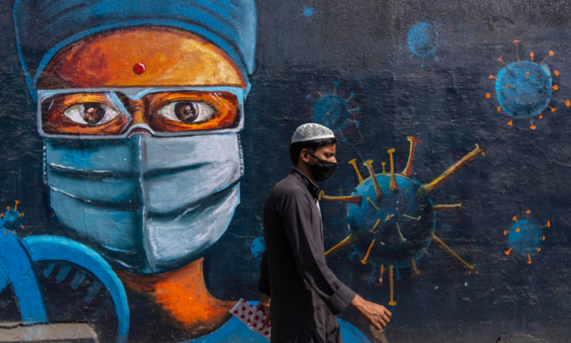 A man walks past a graffiti painted on a wall to create awareness about coronavirus disease, in Mumbai, India. — AP