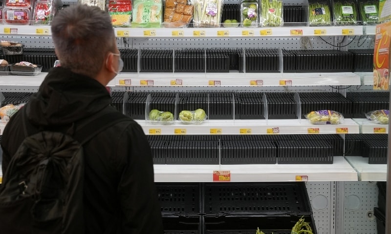 A customer wearing a face mask shops in front of partially empty shelves at a supermarket, following the outbreak of Covid-19 at Sha Tin district, in Hong Kong on February 7. &mdash; Reuters