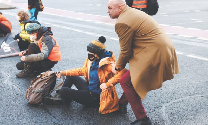 A man removes an activist of Last Generation, a group fighting for protection of the environment, after he blocked the exit of a highway following a demonstration
on Monday.—Reuters A man removes an activist of Last Generation, a group fighting for protection of the environment, after he blocked the exit of a highway following a demonstration
on Monday.—Reuters