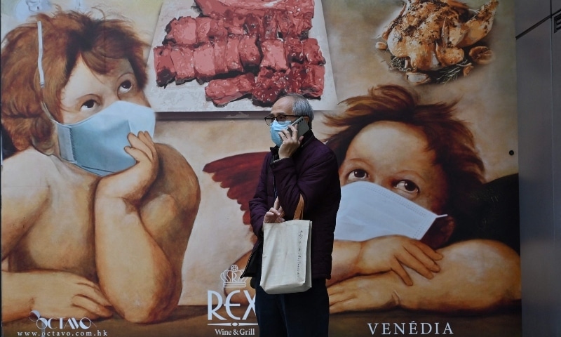 A man talks on the phone in front of a banner for a restaurant in Hong Kong on February 14. &mdash; AFP