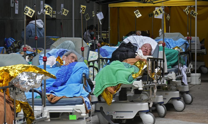 Patients lie on hospital beds as they wait at a temporary holding area outside Caritas Medical Centre in Hong Kong on Wednesday. — AP