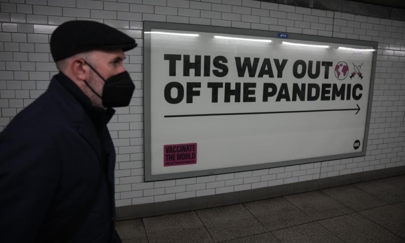 A man wearing a face mask to curb the spread of coronavirus walks past a health campaign poster in an underpass leading to Westminster underground train station in London on Jan 27. — AP