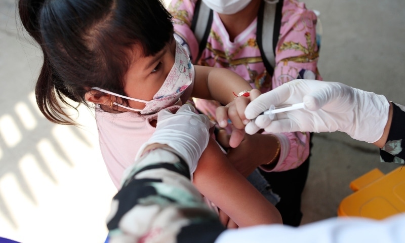 A young girl held by her mother pushes a shaft of a needle as she receives a first dose of Sinovac's Covie-19 vaccine at a health centre outside Phnom Penh, Cambodia on Feb 23. &mdash; AP