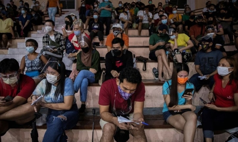 Filipinos use their smartphones while queueing for free vaccination against the coronavirus at San Andres Sports Complex in Manila, on July 21, 2021. — Reuters