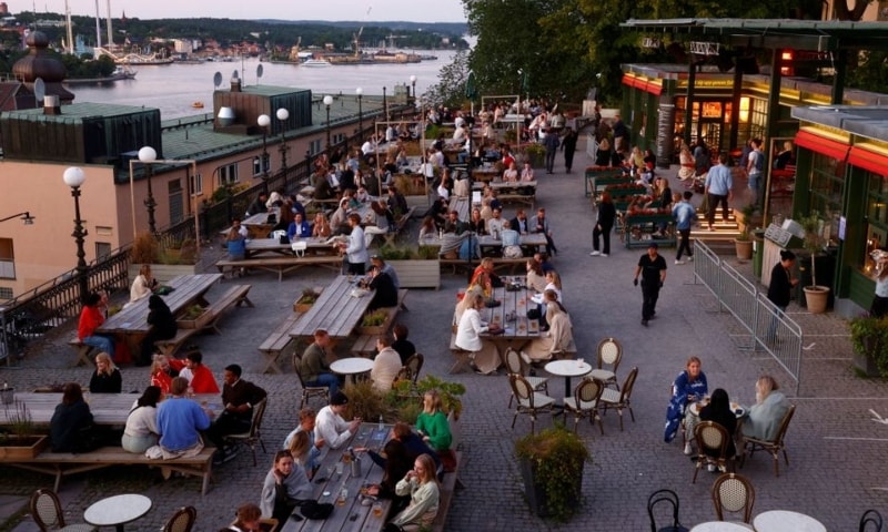 People sit at tables at an outdoor bar in Stockholm, Sweden, on July 1 2021. — Reuters
