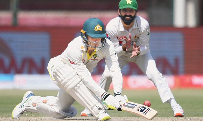 Australia batter Alex Carey plays a reverse sweep as close-in Pakistan fielder Fawad Alam watches during the second Test at the National Stadium on Sunday.—Tahir Jamal/White Star