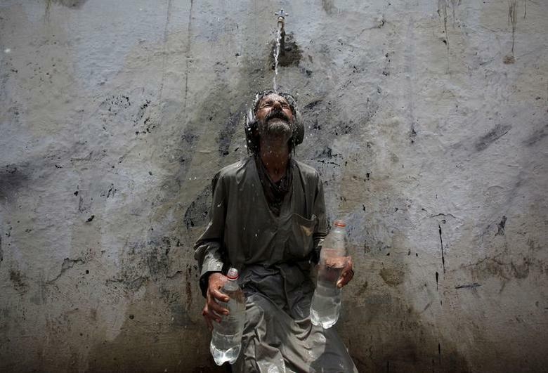 A man cools off from a public tap after filling bottles during intense hot weather in Karachi on June 23, 2015. — Reuters/ File