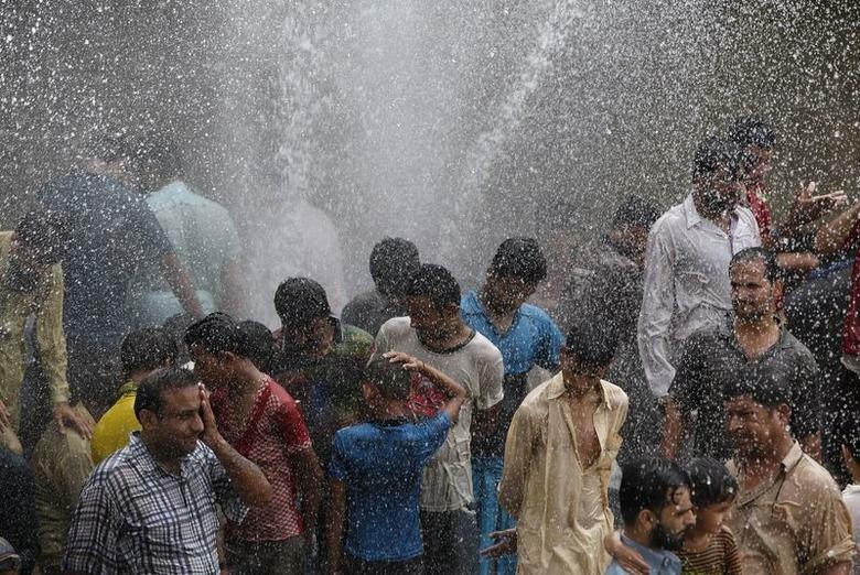 People cool off from the heat as they are sprayed with water jetting out from a leaking water pipeline in Karachi in 2015. — Reuters/ File